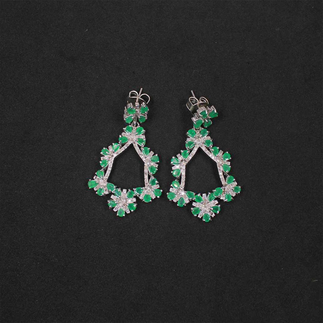 Pair of green and silver earrings on a black background