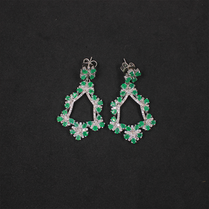 Pair of green and silver earrings on a black background
