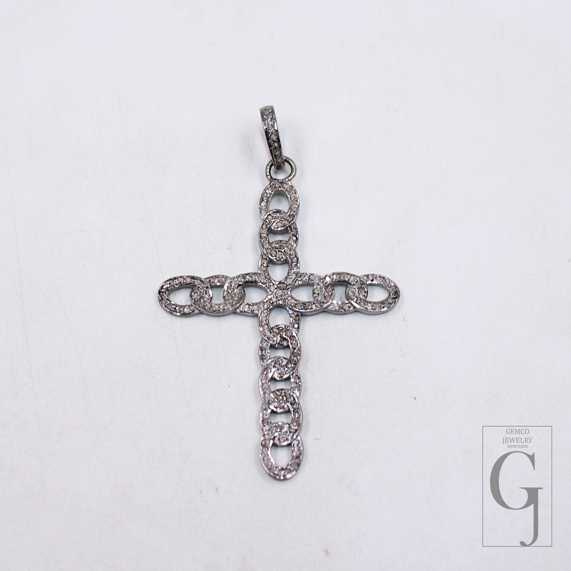 A sterling silver cross pendant with rose cut pave diamond design, displayed against a white background.
