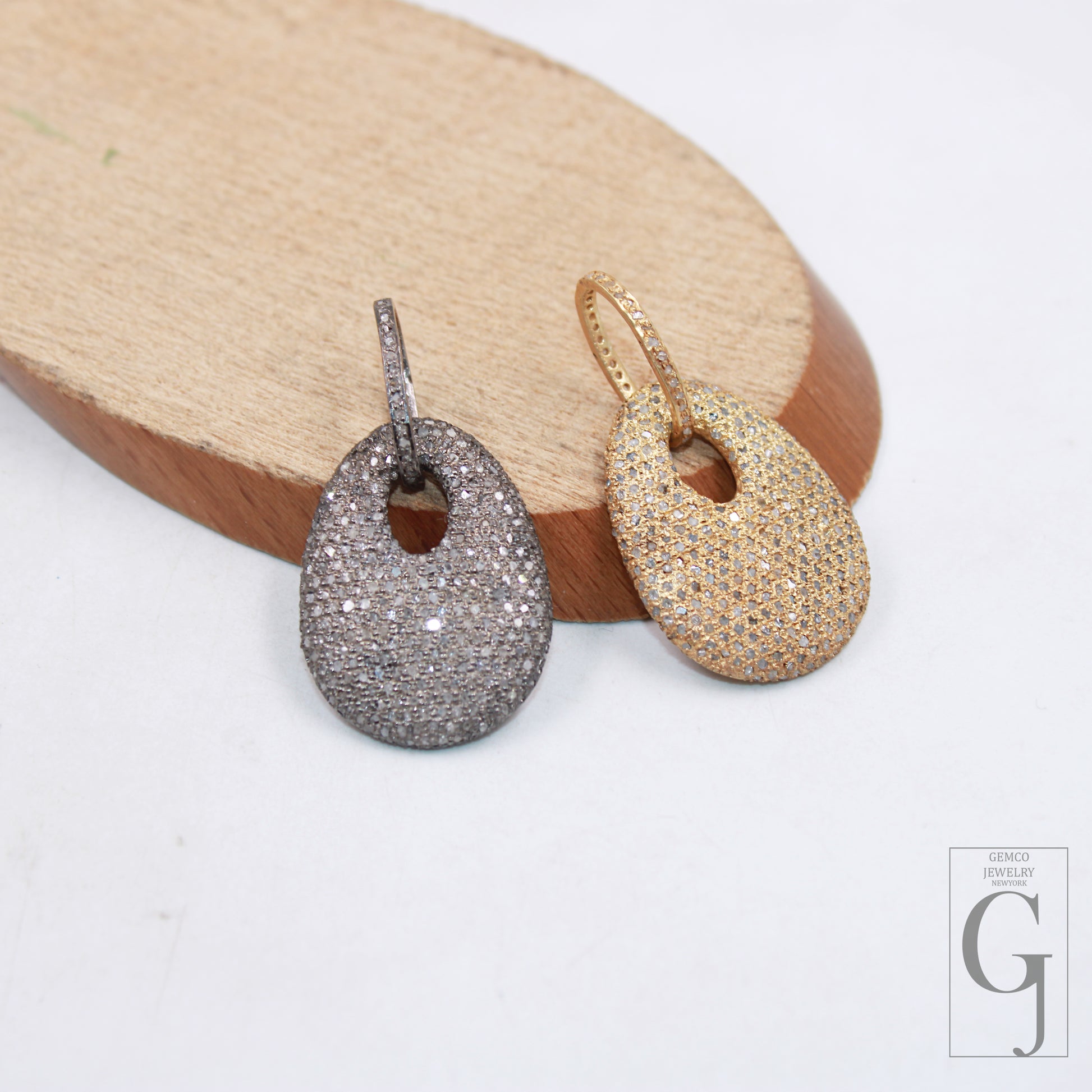 Two dog tag pendants with 925 sterling silver, one with a rose cut pave diamond surface, and the other with a clear, sparkling diamond surface, displayed against a wooden background.