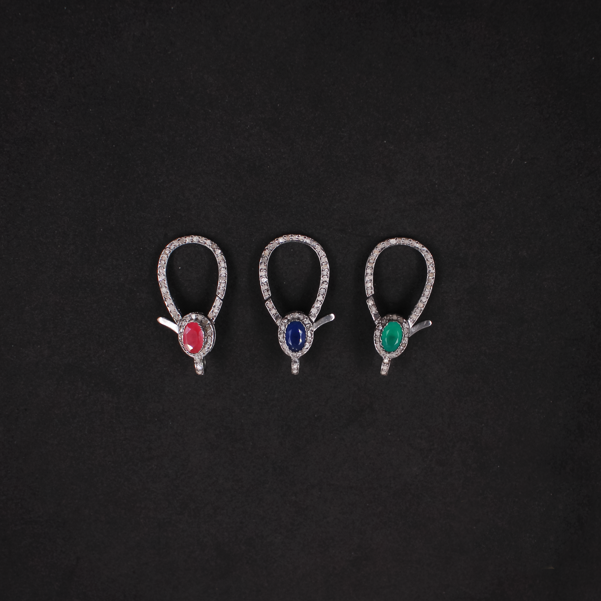 Three pairs of earrings with gemstones on a black background