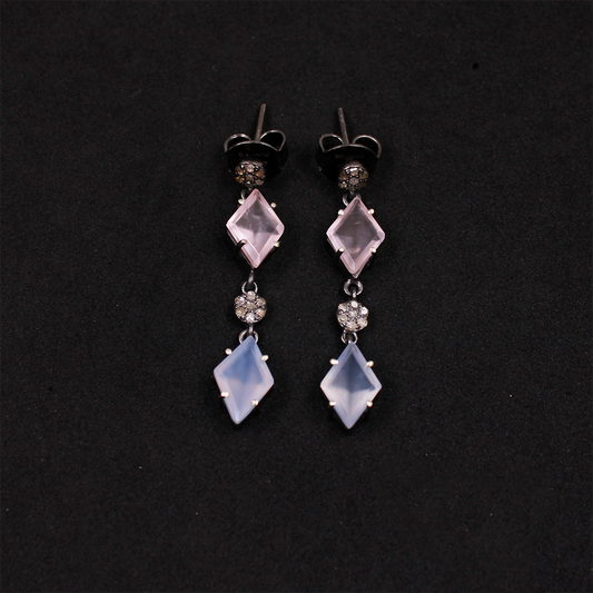 Pair of earrings with diamond-shaped gemstones on a black background