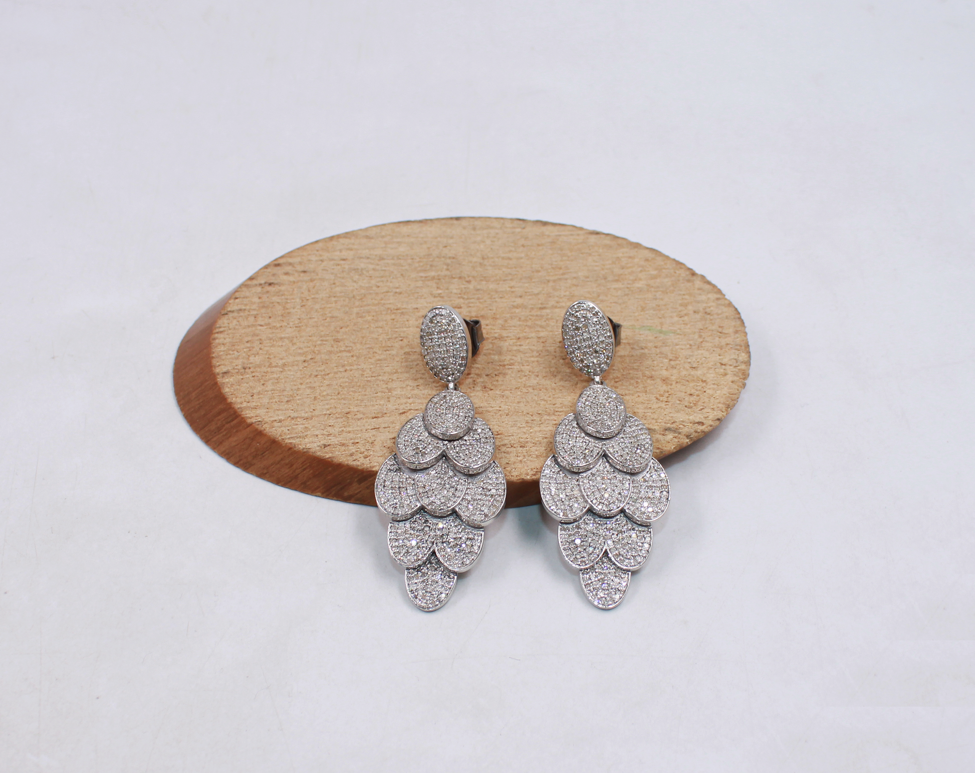 Pair of silver earrings on a wooden disc with a light background