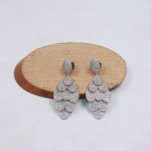 Pair of silver earrings on a wooden disc with a light background