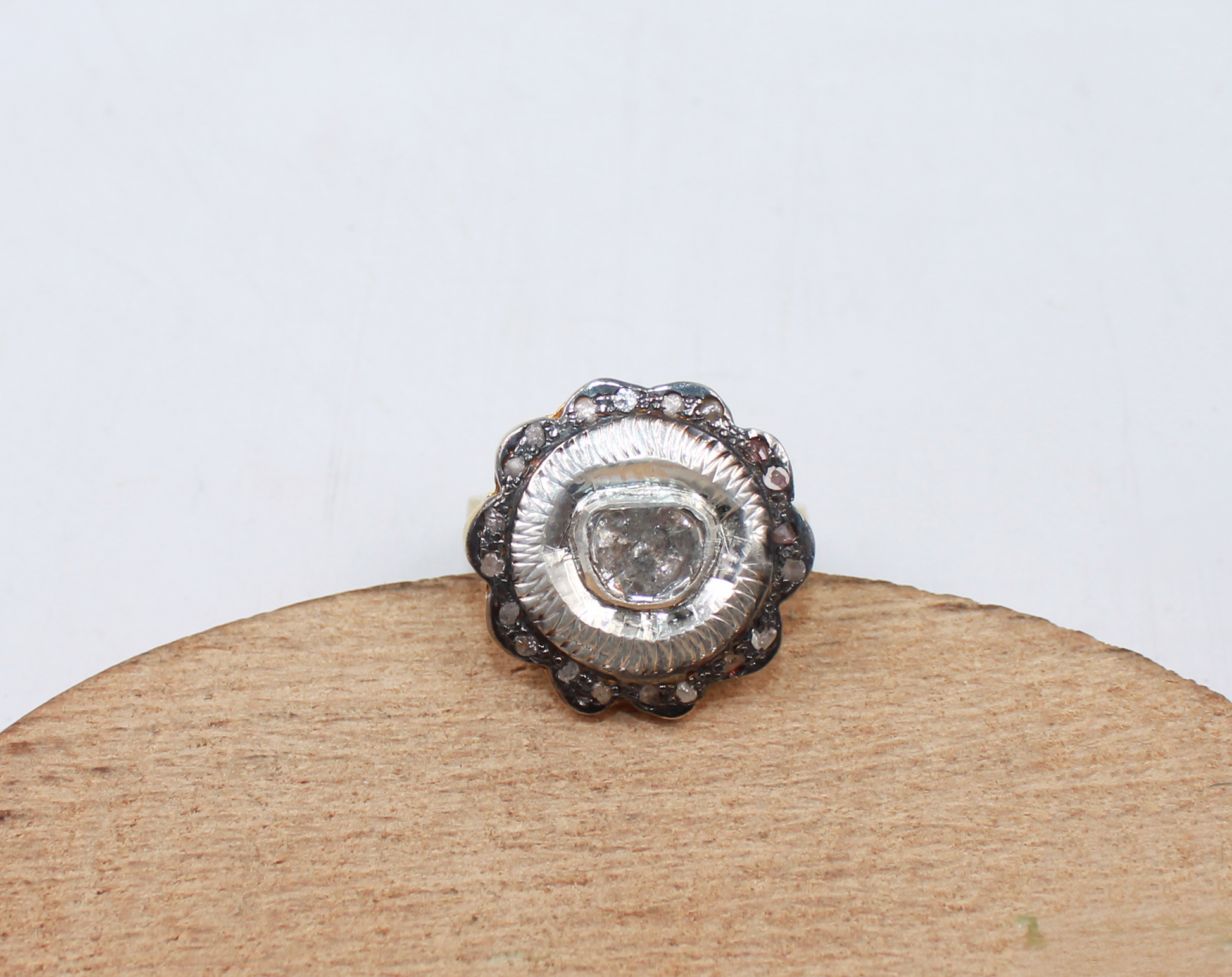 Silver ring with a central stone on a wooden stand against a white background