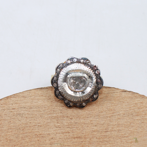 Silver ring with a central stone on a wooden stand against a white background