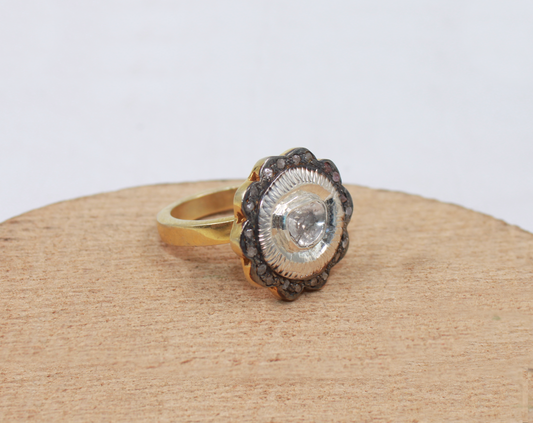 Gold ring with a central gemstone on a beige surface