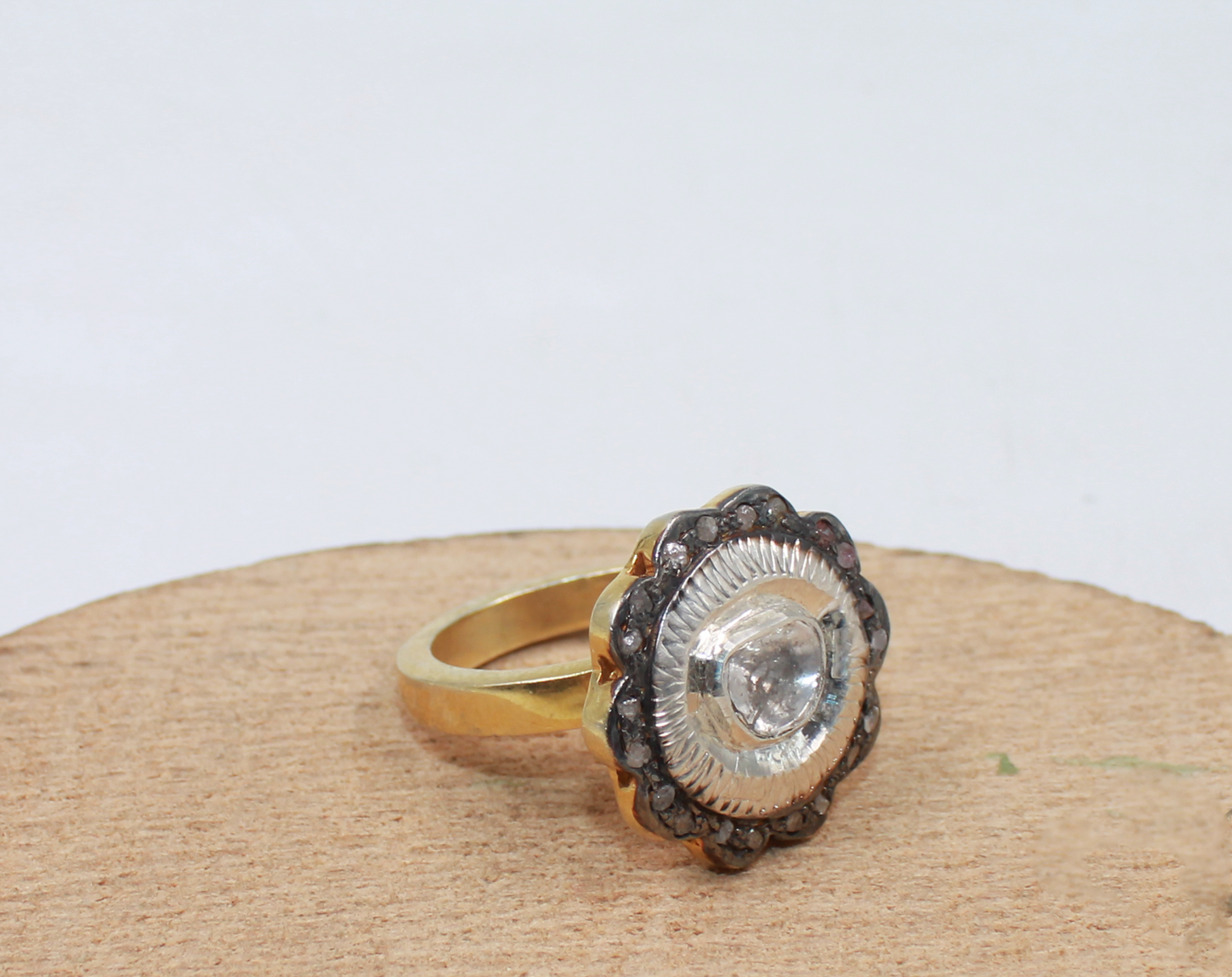 Gold ring with a large central gemstone on a wooden surface