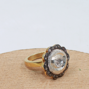 Gold ring with a large central gemstone on a wooden surface
