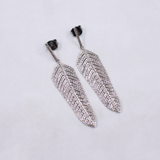 Pair of silver feather-shaped earrings on a light gray background