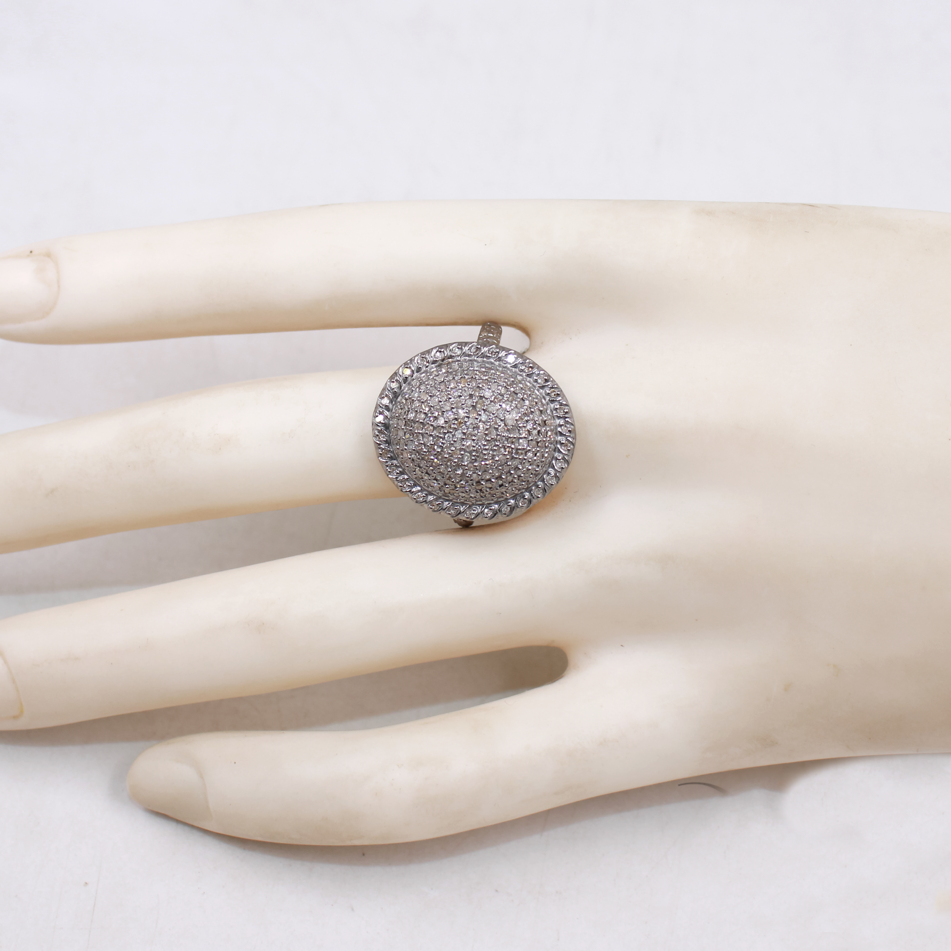 Silver ring with gemstones on a mannequin hand against a white background