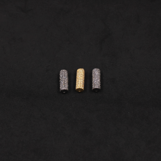 Three cylindrical beads, two silver and one gold, on a black background