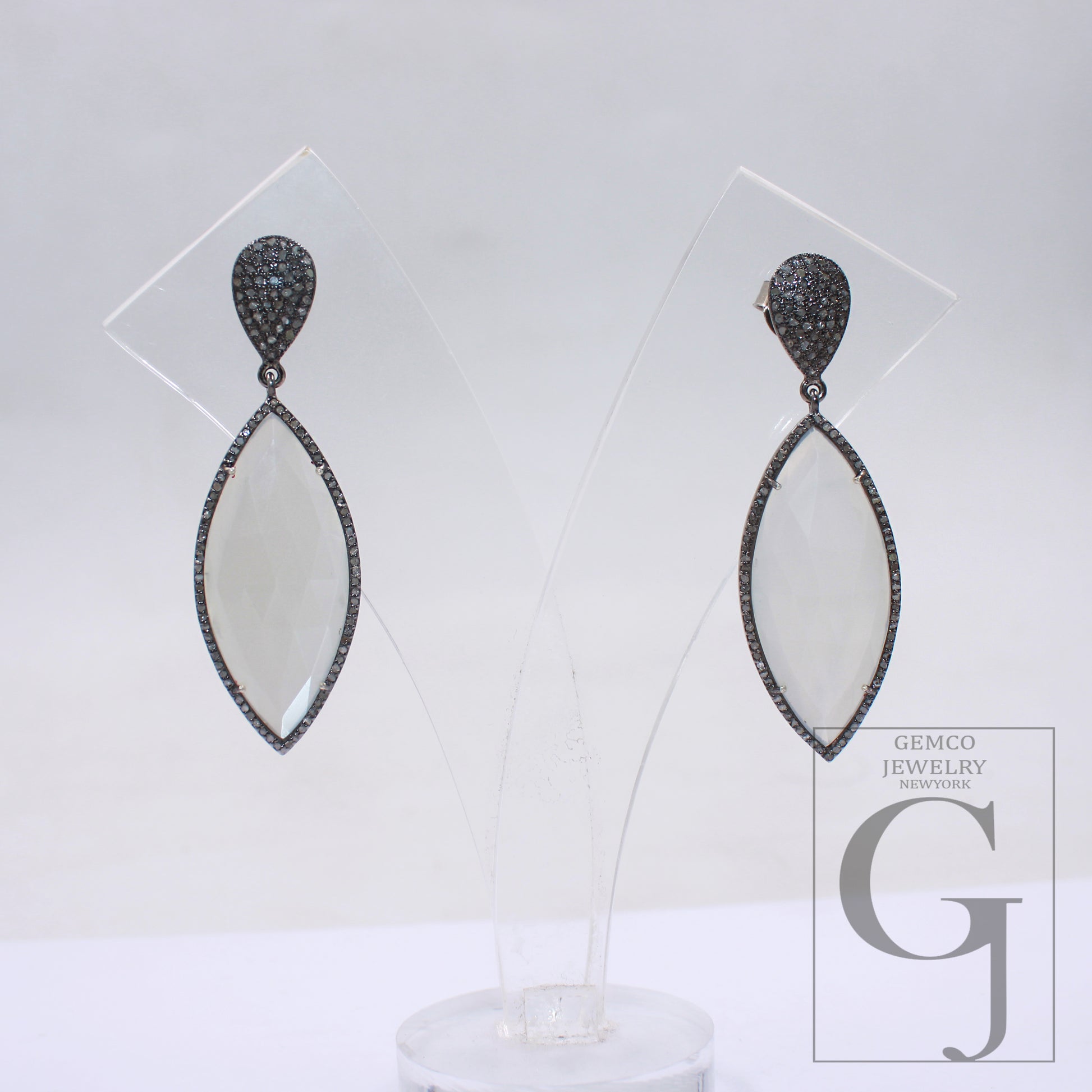 Close-up of handmade moonstone and rosecut diamond teardrop earrings.