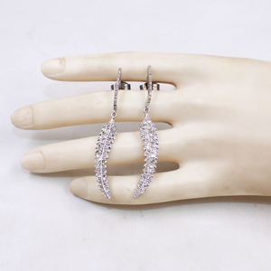 Silver leaf-shaped earrings on a mannequin hand against a white background