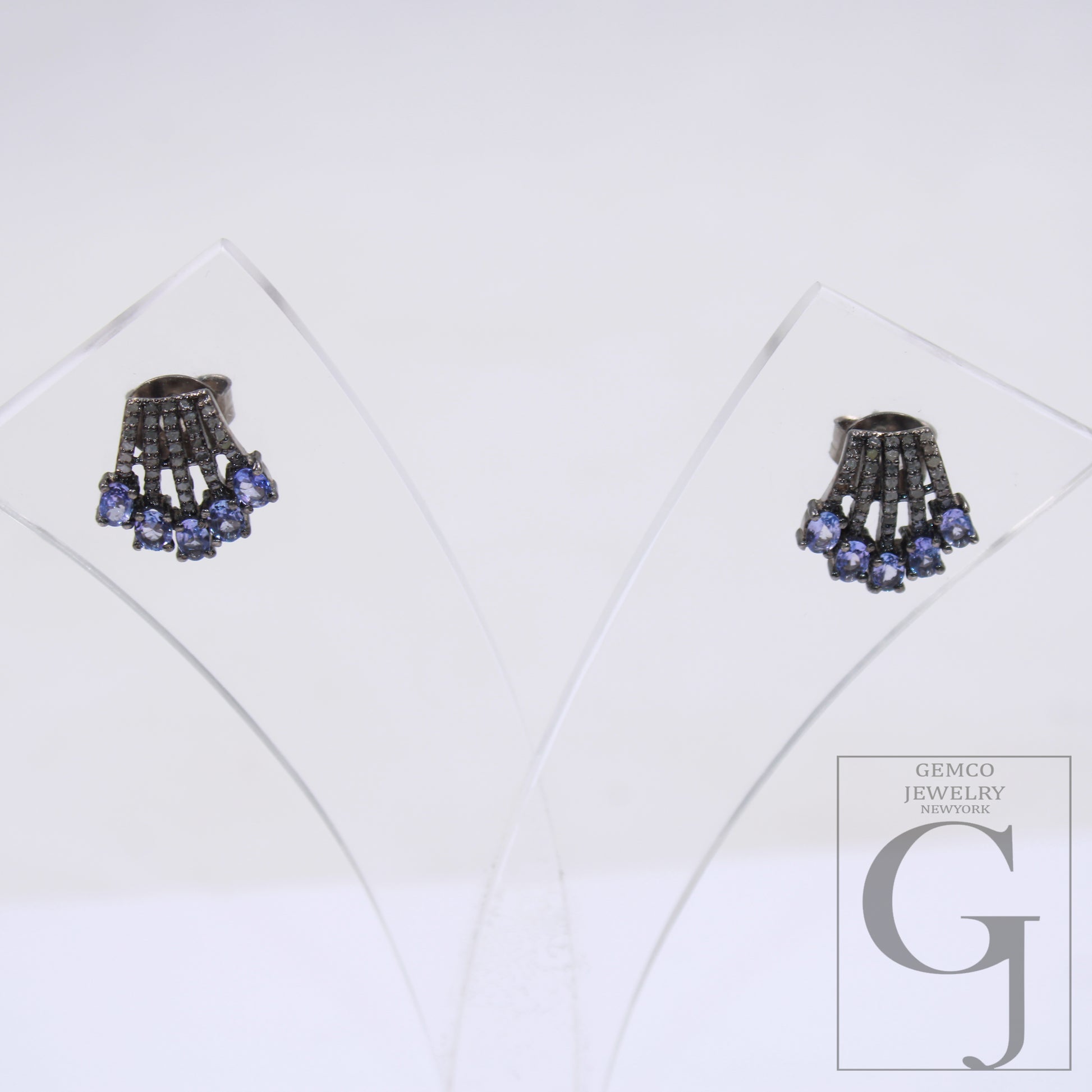 This image displays a pair of elegant earrings, presented in a clear, protective case that enhances their vibrant colors and intricate design. The earrings feature a striking combination of blue and clear beads, with a central, ornate ring that adds sophistication to the overall aesthetic.