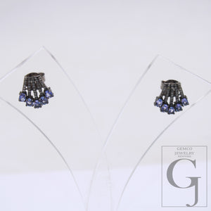 This image displays a pair of elegant earrings, presented in a clear, protective case that enhances their vibrant colors and intricate design. The earrings feature a striking combination of blue and clear beads, with a central, ornate ring that adds sophistication to the overall aesthetic.