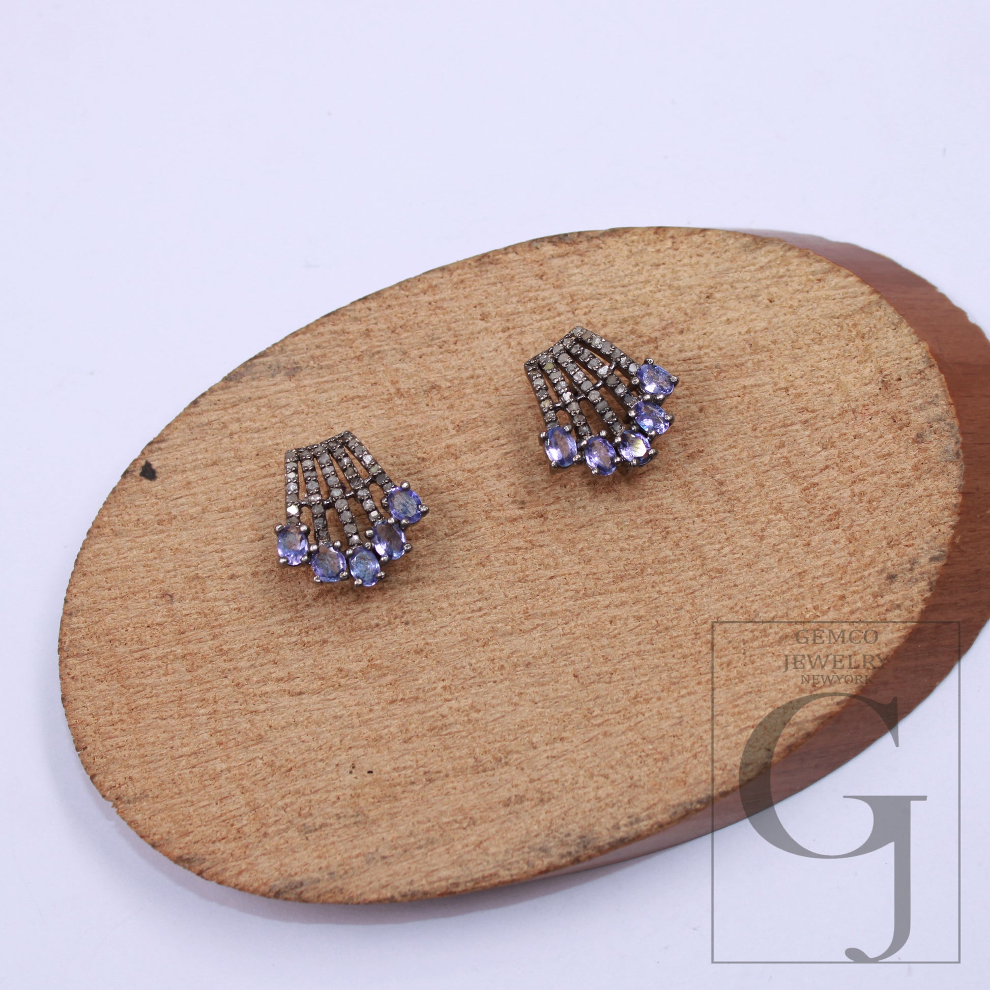 Elegant small stud earrings with purple tanzanites and rosecut diamonds – close-up.