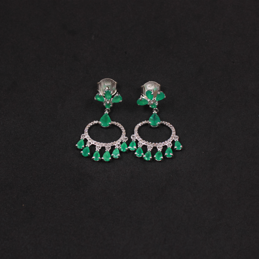 Pair of earrings with green emerald gemstones on a black background