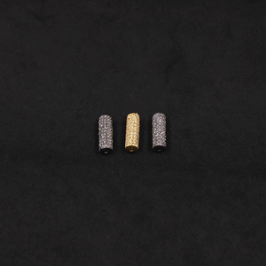 Three cylindrical beads, two silver and one gold, on a black background