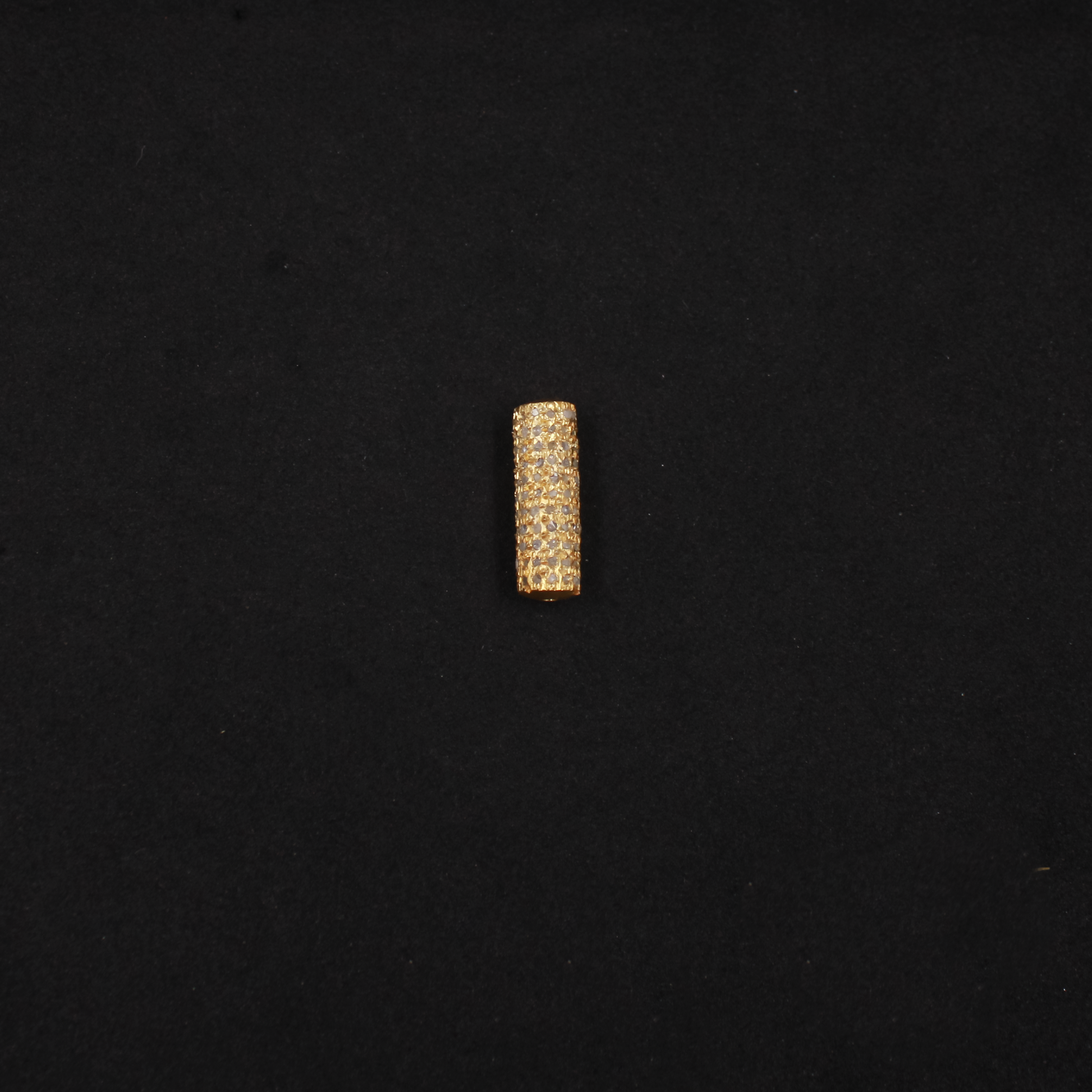 Gold cylindrical bead on a black background