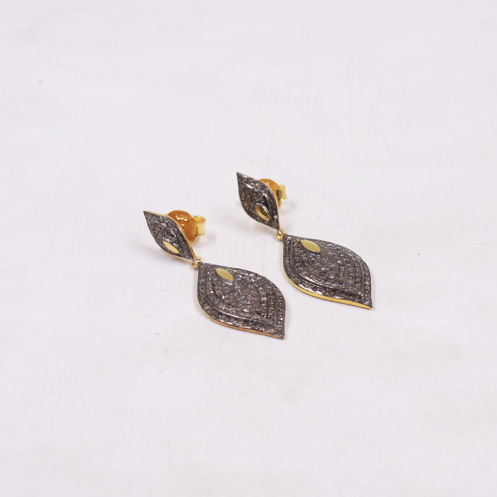 Pair of gold and black diamond-studded earrings on a white background