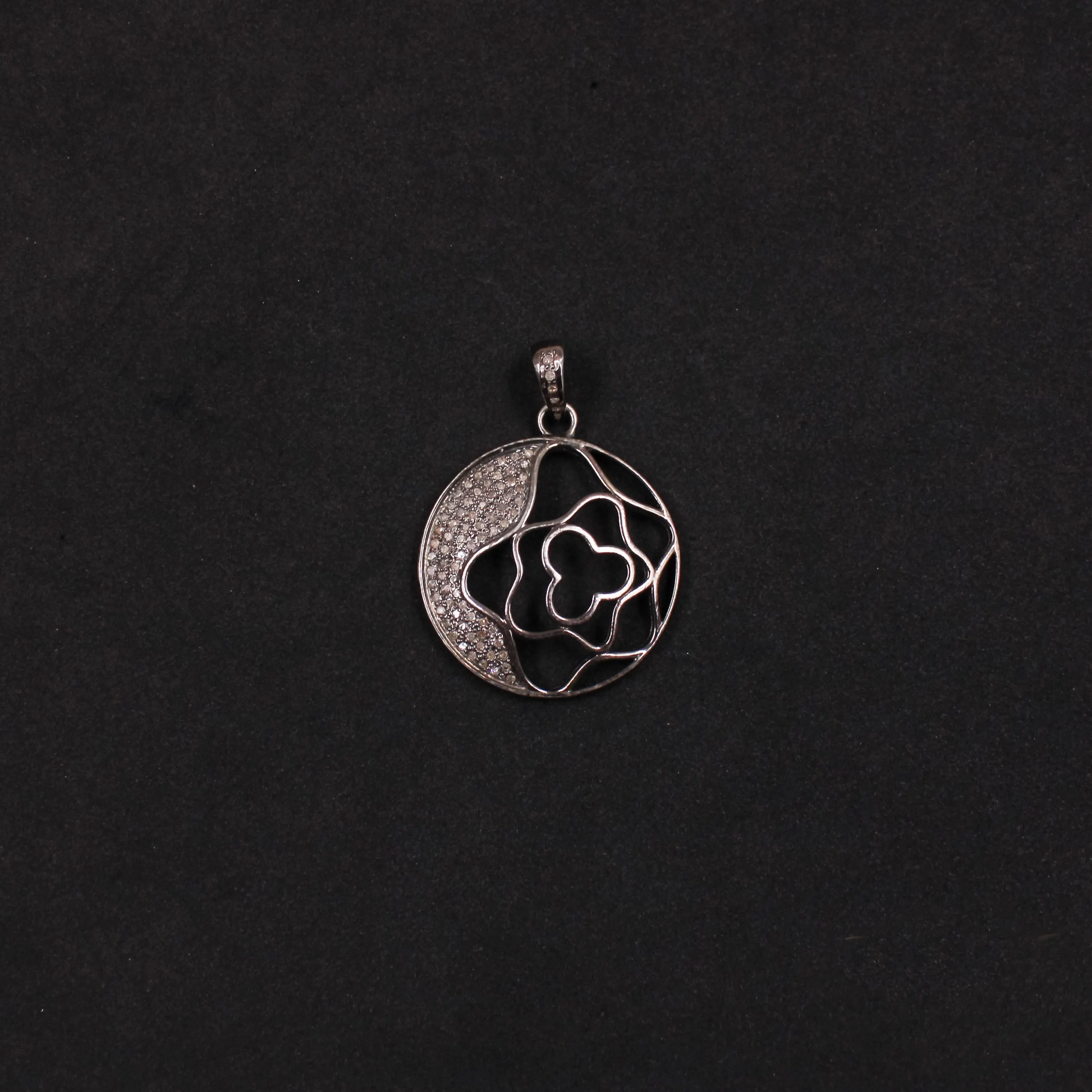 Silver pendant with floral design on a black background