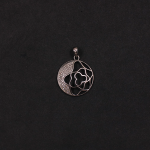 Silver pendant with floral design on a black background