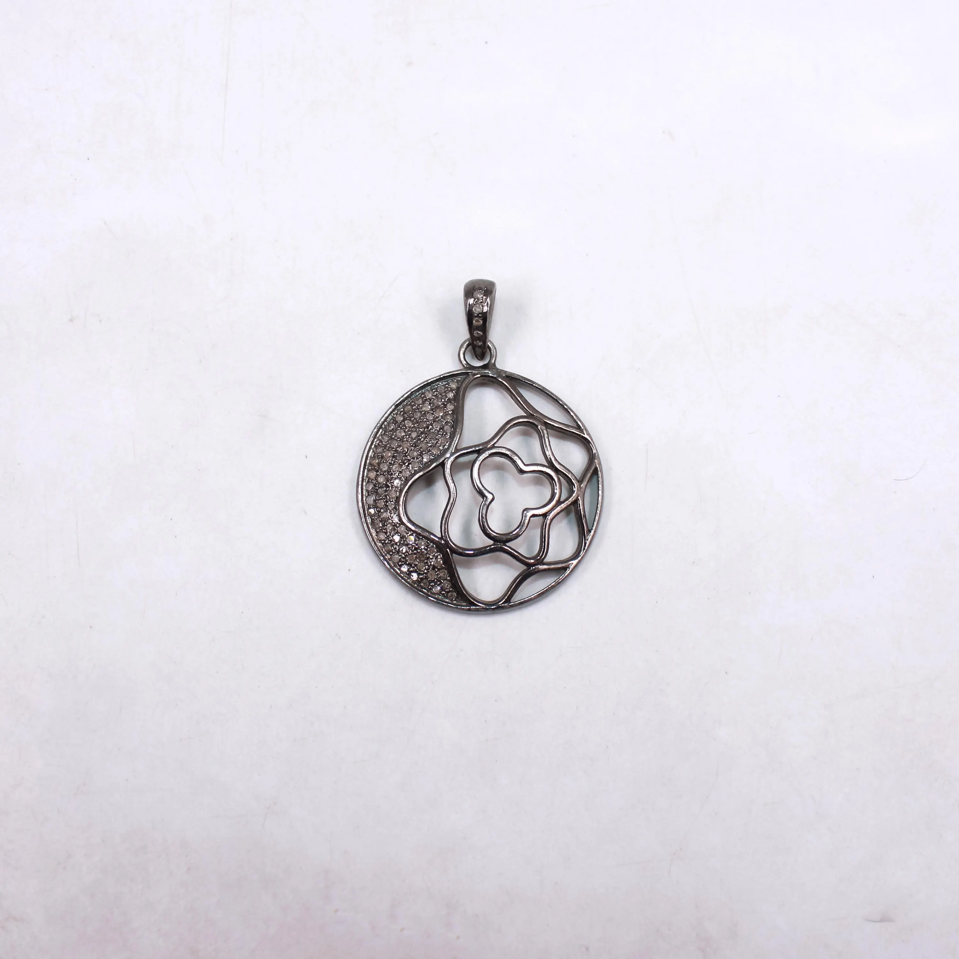 Silver pendant with floral design on a white background