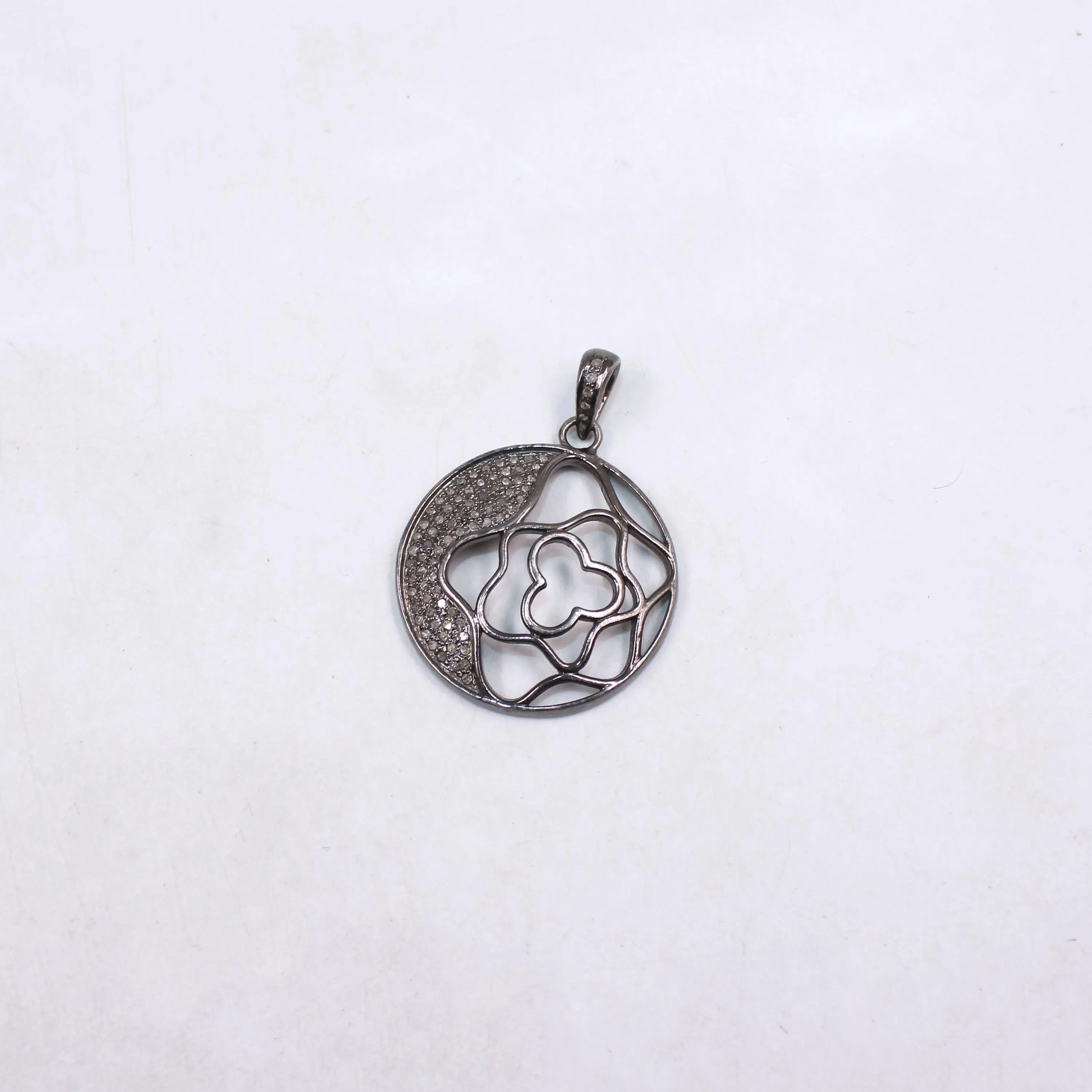 Silver pendant with intricate design on a white background