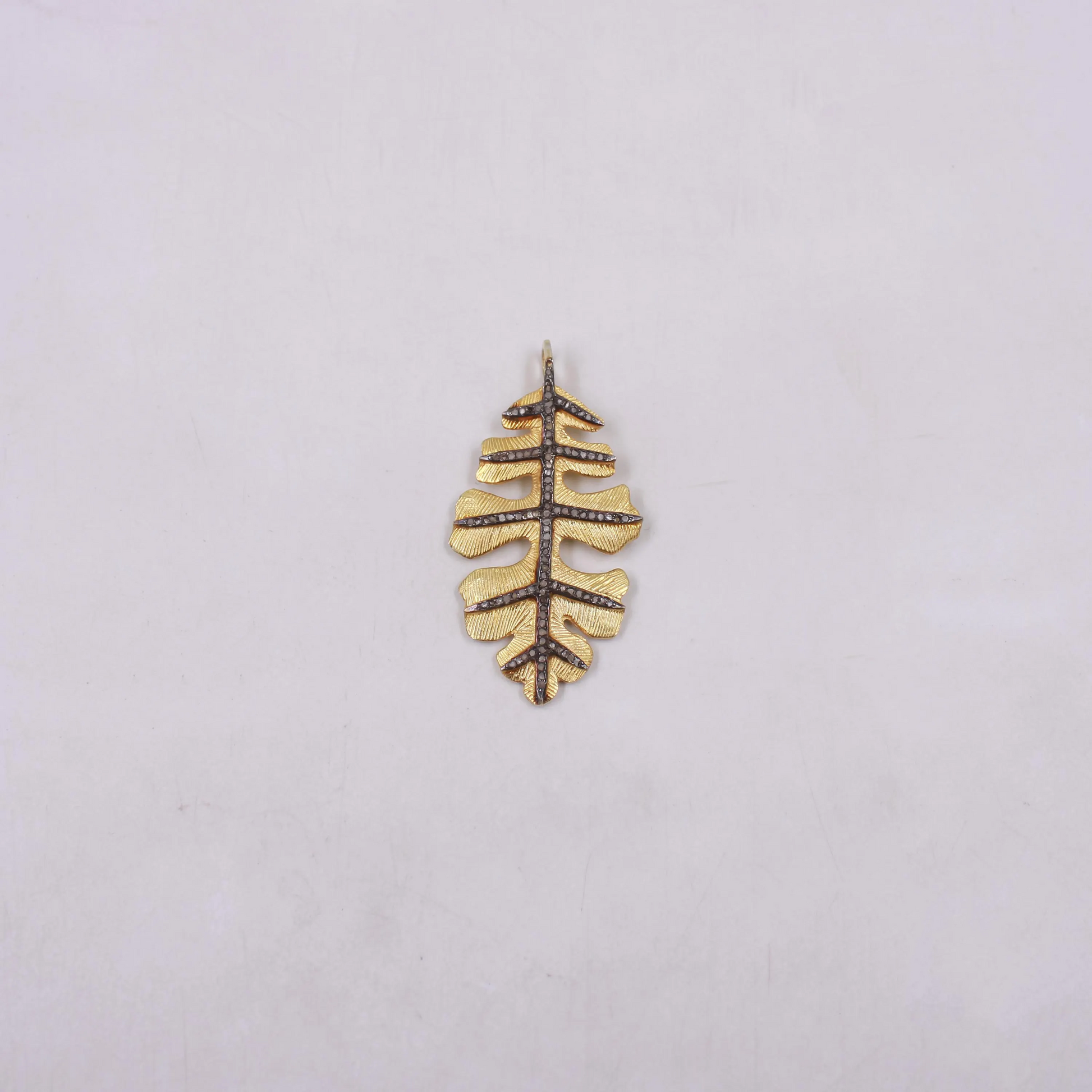 Gold leaf-shaped pendant on a light gray background