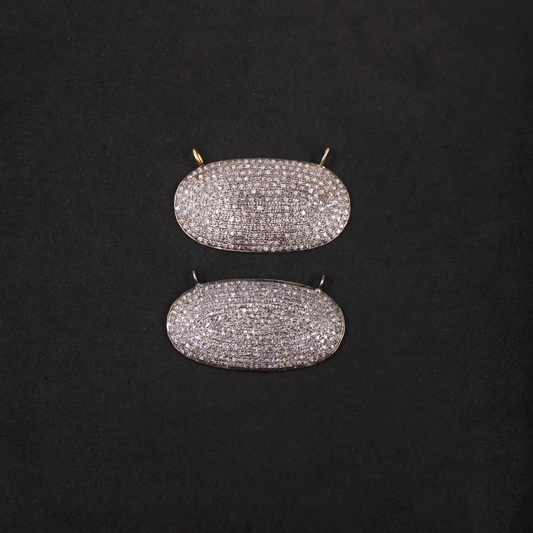 Pair of diamond-studded oval pendants on a black background