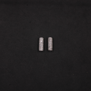Two small cylindrical metal objects on a black background