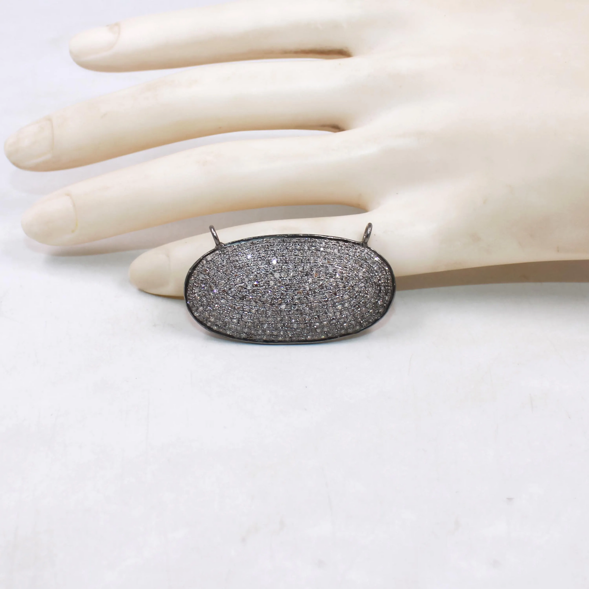 Silver pendant on a mannequin hand against a white background