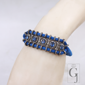 Blue bracelet with gemstones on a wrist against a light gray background
