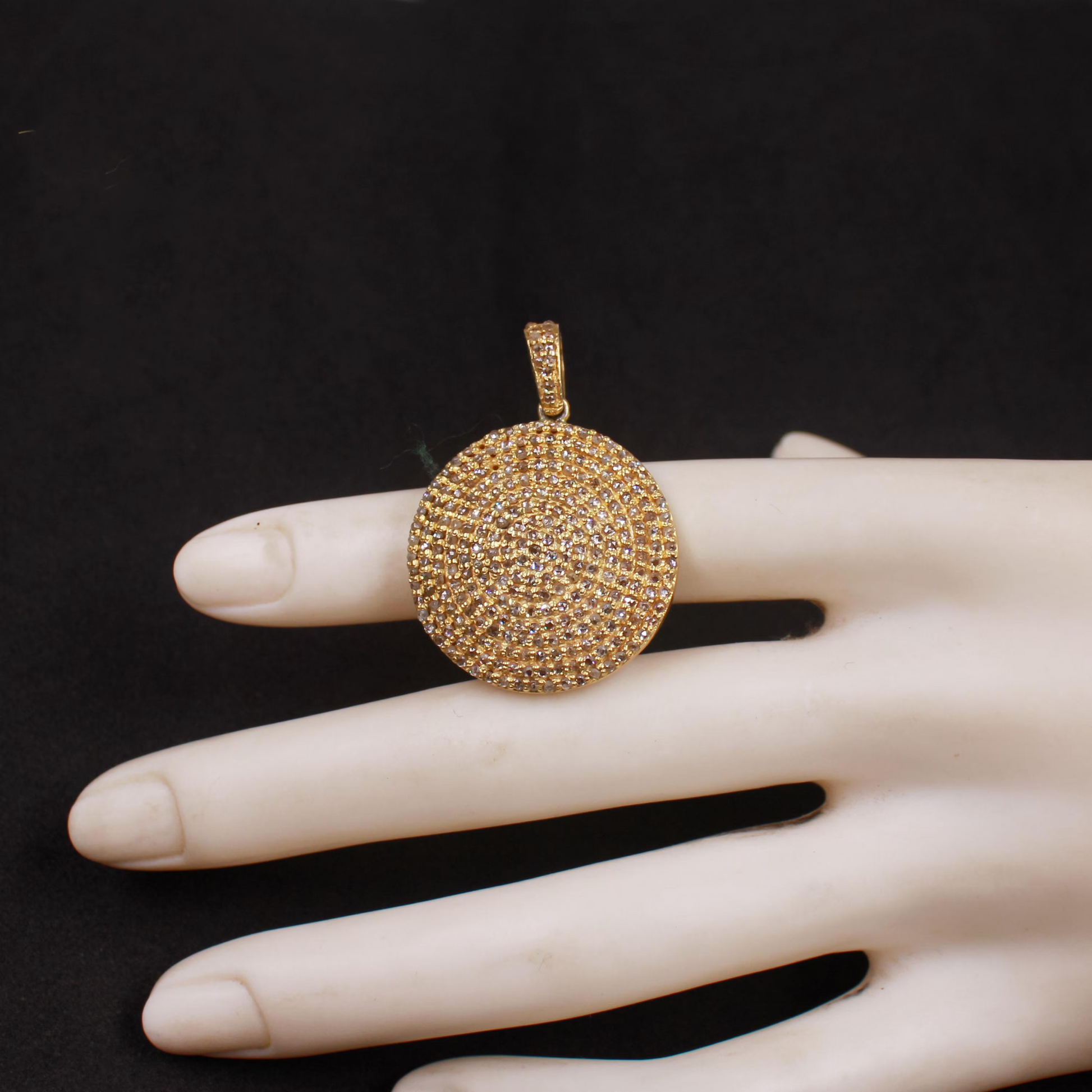 Gold pendant on a mannequin hand against a black background