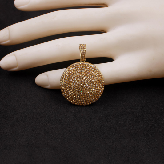 Gold pendant on a mannequin hand against a black background