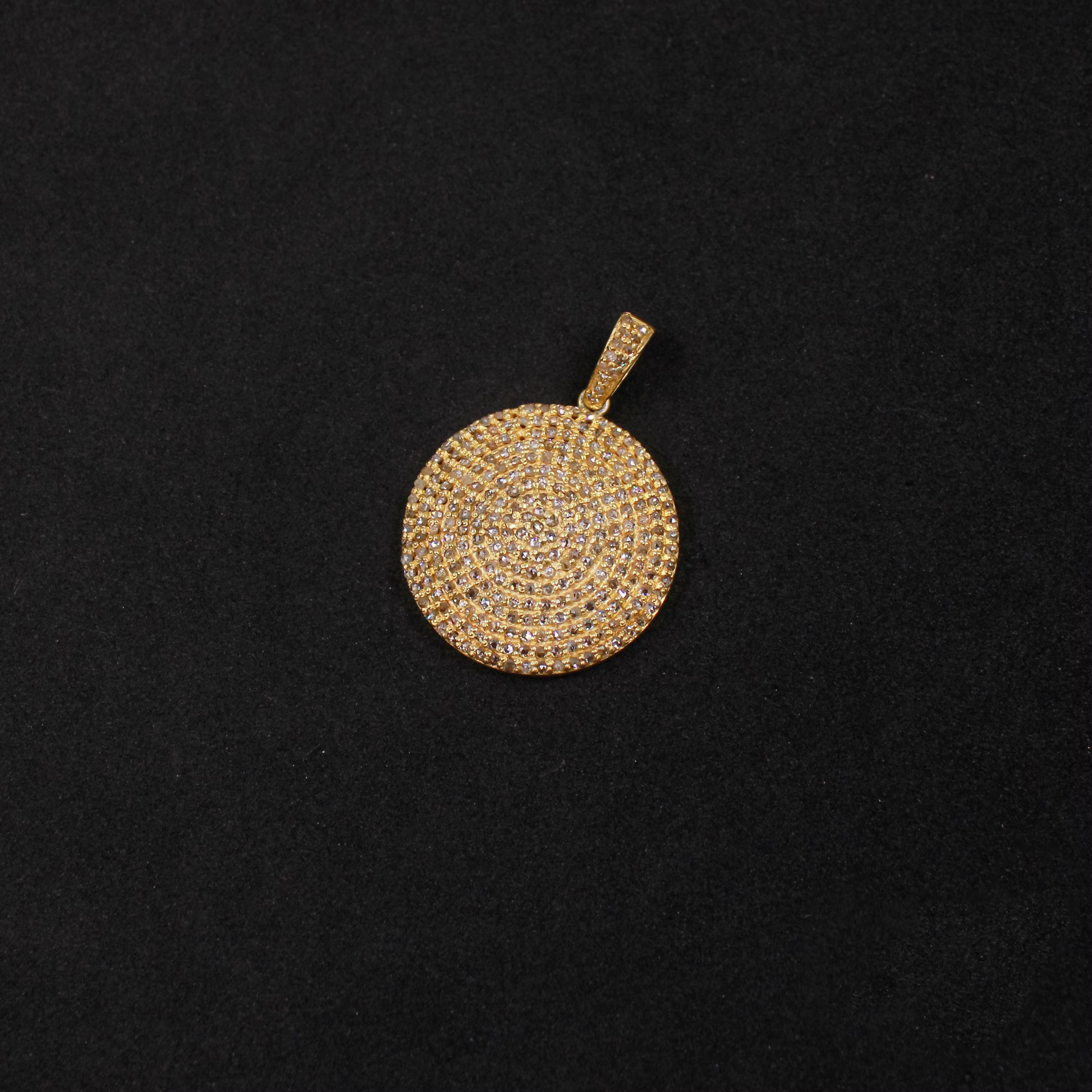 Gold pendant with circular design on a black background