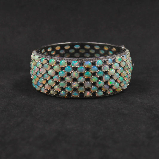 Opal bracelet with black and gold accents on a dark background