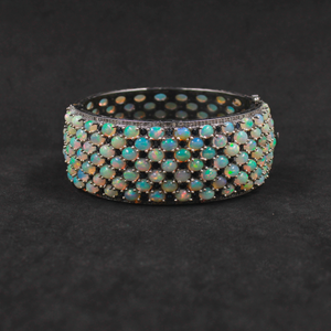 Opal bracelet with black and gold accents on a dark background