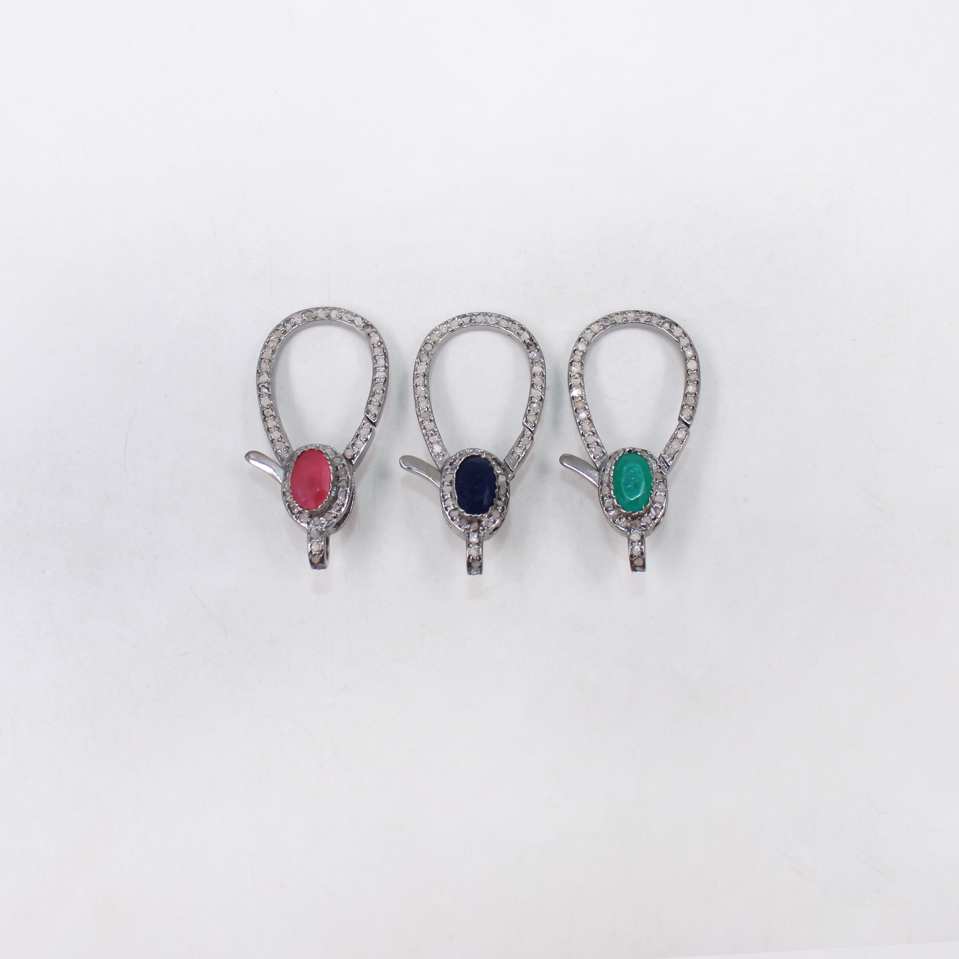 Three diamond earrings with colored gemstones on a white background
