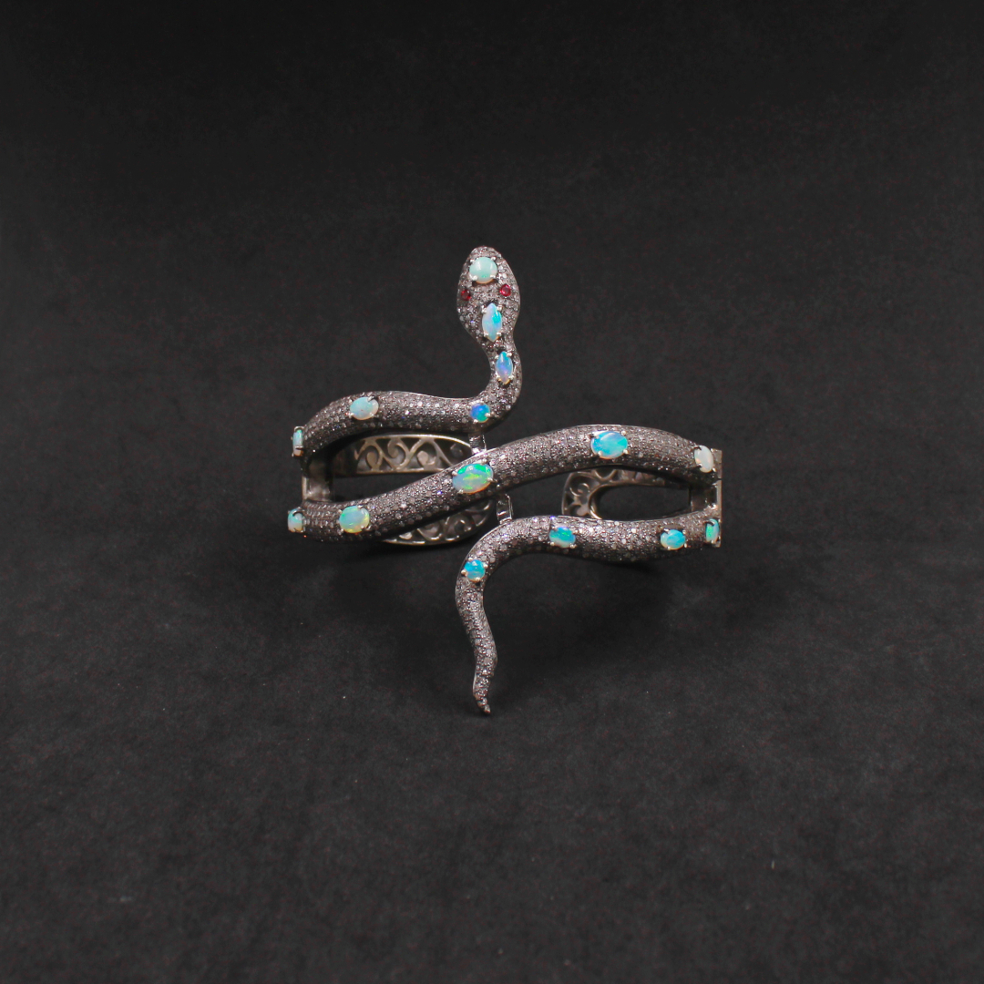 Decorative snake-shaped object with gemstones on a black background