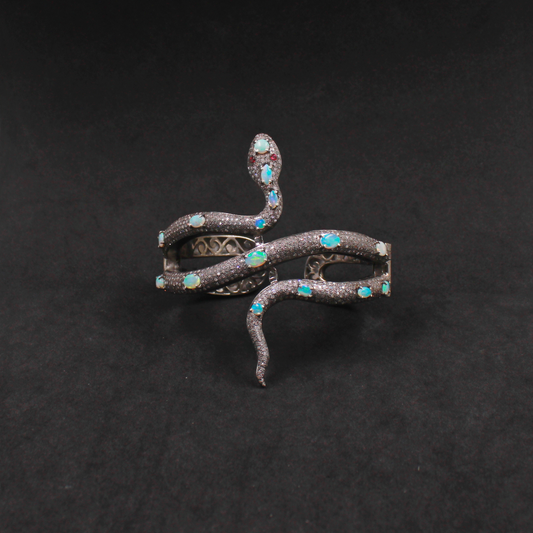 Decorative snake-shaped object with gemstones on a black background