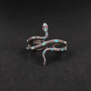 Decorative snake-shaped object with gemstones on a black background