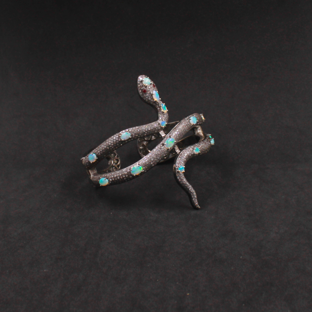 Silver snake brooch with turquoise stones on a dark background