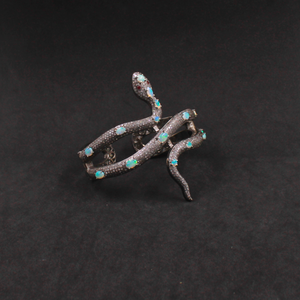 Silver snake brooch with turquoise stones on a dark background