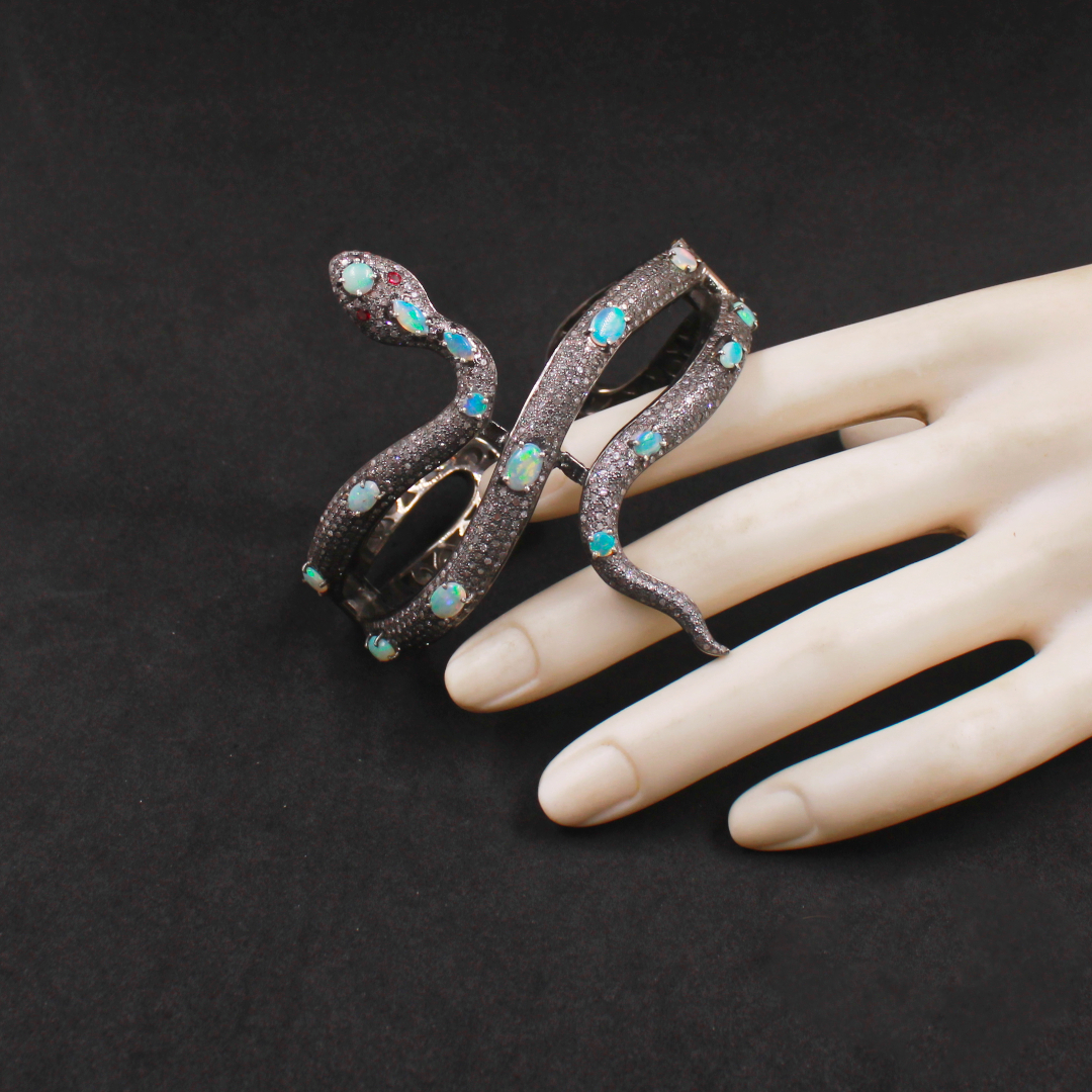 Decorative snake-shaped ring with turquoise stones on a mannequin hand against a black background