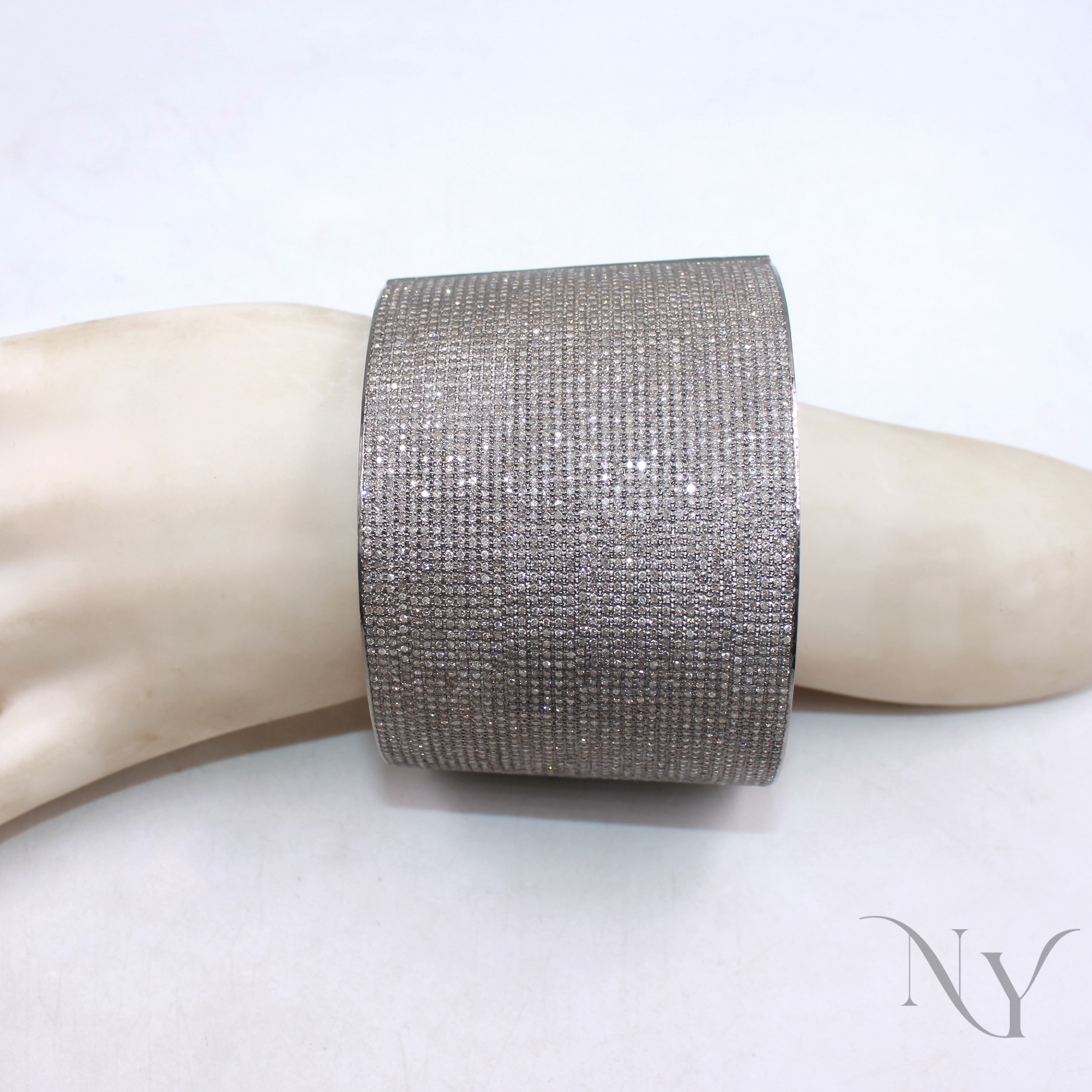 Silver glittery cuff bracelet on a mannequin arm with a plain background