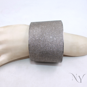 Silver glittery cuff bracelet on a mannequin arm with a plain background