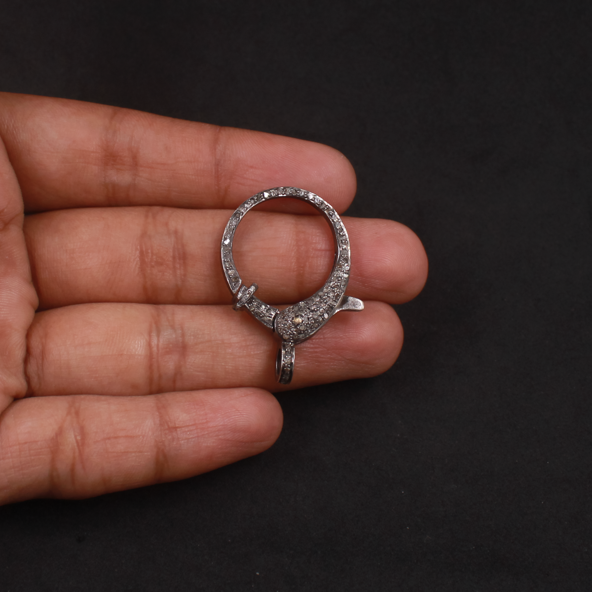 Silver ring held in a hand against a black background