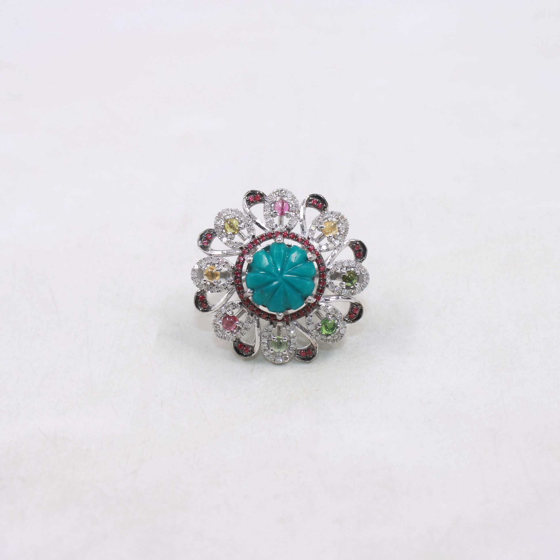 Ring with a turquoise center stone and multicolored gemstones on a white background